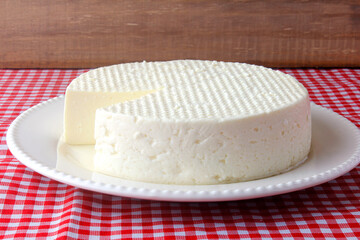fresh brazilian white minas cheese on white plate over breakfast table with towel