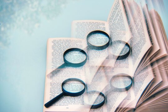 Digital Composite Image Of Magnifying Glass And Book On Blue Background