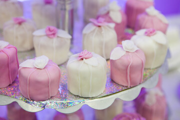 Cupcakes and other cakes with icing on glowing paper on plate