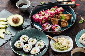 Delicious rolls, sushi and maki on a dark wooden Board with chopsticks. On black rustic background