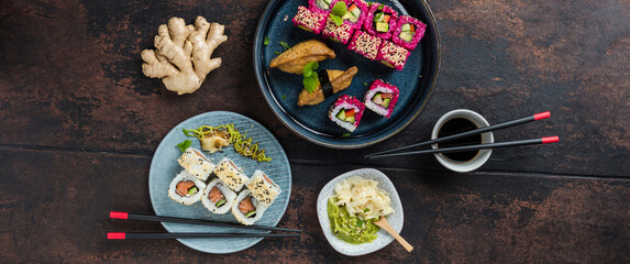 Delicious rolls, sushi and maki on a dark wooden Board with chopsticks. On black rustic background