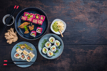 Delicious rolls, sushi and maki on a dark wooden Board with chopsticks. On black rustic background