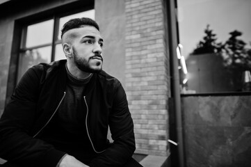 Portrait of stylish arab beard man wear grey turtleneck and black jaket. Arabian model guy squat.