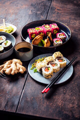 Delicious rolls, sushi and maki on a dark wooden Board with chopsticks. On black rustic background