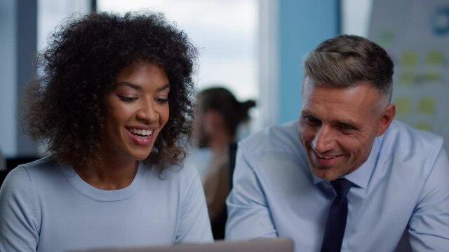Smiling businesswoman and businessman looking at good work results in office