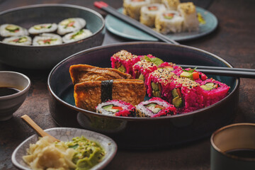 Delicious rolls, sushi and maki on a dark wooden Board with chopsticks. On black rustic background