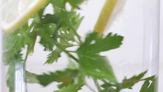 macro slow motion of fresh organic carrot, celeri and lemon turning in glass with water. Clean fresh organic fruits for healthy life concept