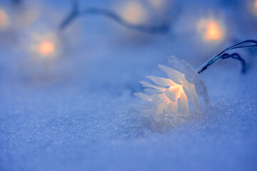 Christmas garland in the form of cones on the snow in the evening. New year festive background