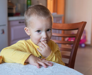 A little boy sits at a table and eats