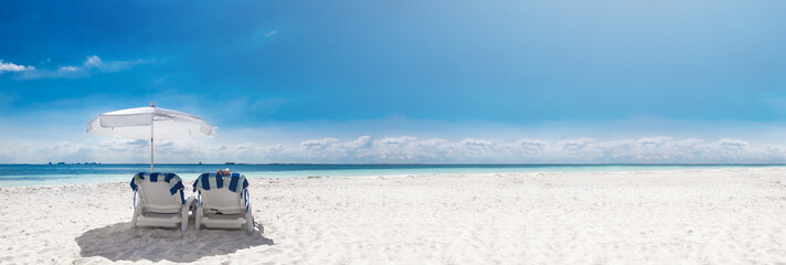Caribbean beach with sun umbrella and sunbeds. Vacation on tropical beach