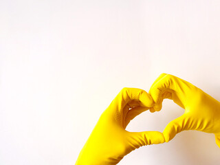 Yellow latex gloves make heart on white background. Concept support and disinfection, copyspace