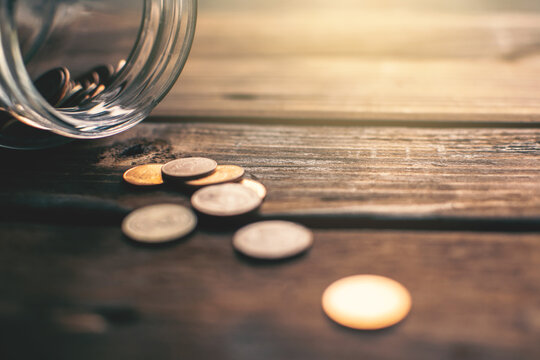 Close-up Of Coins Falling From Jar On Table