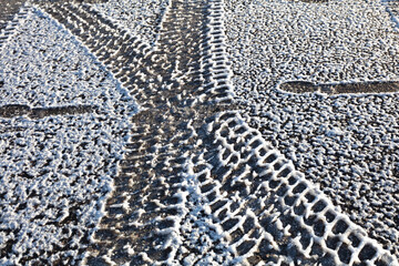 frozen footprints on the road and the asphalt is covered with frost, Concept: first frost, slippery road