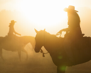 Silhouette of cowgirl on horse in morning