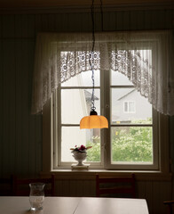 Yellow hanging lamp and window and lace curtain background