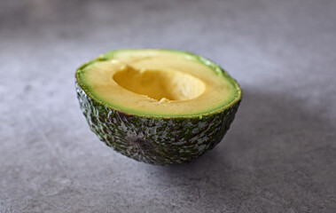 A high angle shot of a half of an avocado on a rough surface