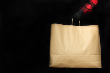 a man in black protective gloves holds a bag with purchases from the store during The black Friday