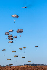 Military parachutist paratroopers parachute jumping out of a air force planes on a clear blue sky...