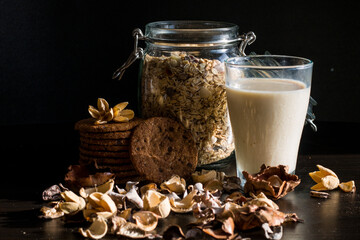 Serving healthy morning breakfast with corn flakes Whole grains muesli, fresh milk in a glass and Pile of Delicious Chocolate homemade Chip Cookies on a vintage dark background. Aesthetic composition