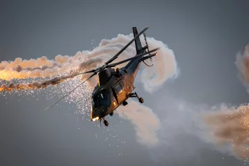 Poster Army helicopter in flight firing off defensive flare decoys at dusk. © VanderWolf Images