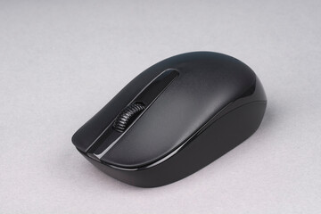 Black wireless optical mouse on a gray background.