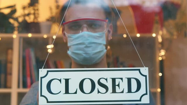 Businessman closing business activity due to covid-19 lockdown turing closed sign on door