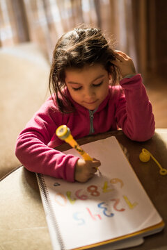 Little girl drawing and doing homework at home