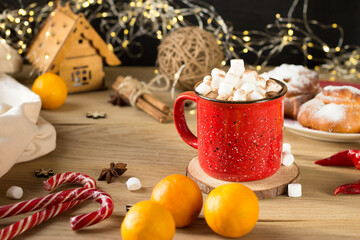 a red mug with marshmallows inside is on the table. cocoa is poured into a mug and sprinkled with...