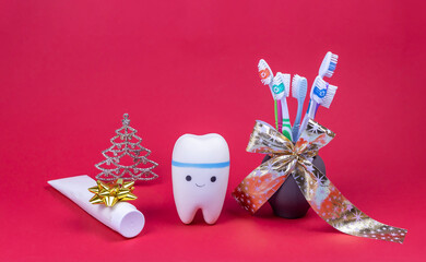 toy model of a tooth, a bouquet of toothbrushes and toothpaste on a red background