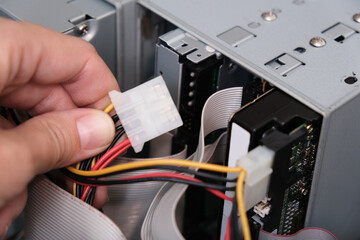 Hands of a technician pluging the cable while computer rapair and fixing