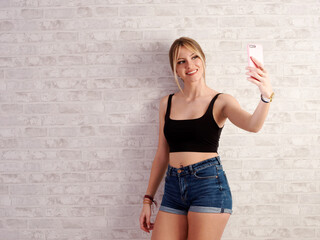 Young and pretty woman taking a self-portrait with the mobile