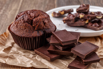Chocolate cupcake with icing and chocolate bar in Dark lighting,Homemade delicious chocolate muffin on wooden background close-up