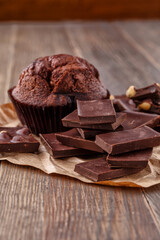Chocolate cupcake with icing and chocolate bar in Dark lighting,Homemade delicious chocolate muffin on wooden background close-up