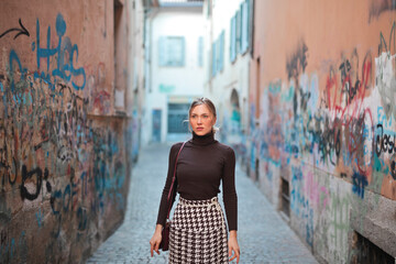 young woman walks in an alley full of graffiti
