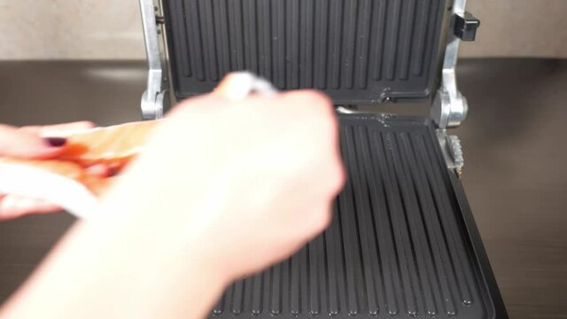 Puting a piece salmon fish on the grid electric grill