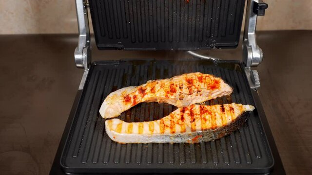 Two pieces salmon fish are cooking on the electric grill