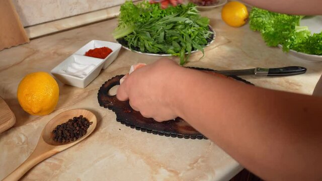 Woman's hand pours ground red pepper on two pieces salmon fish