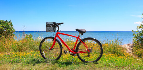 Fototapeta na wymiar Red bike in grass by the lake Huron in Mackinac Island, Michigan