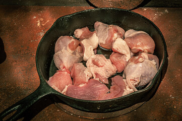 prepare meat in a cast-iron frying pan standing on a rusty wood-burning stove