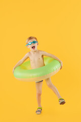Portrait of smiling happy child boy in swimming goggles with neon inflatable rubber circle having fun isolated on yellow background. Summer vacation6 funny face