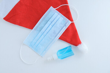 Red Christmas Santa hat medical protective mask and hand sanitizer isolated white background.