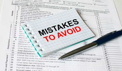 Obraz premium Notepad with text Mistakes To Avoid lying on financial tables with a pen