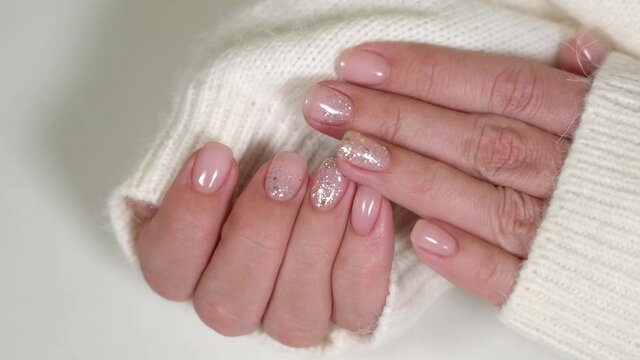 Closeup top view 4K video of beautiful faded colors trendy manicure of pink nails with glossy shiny silver design isolated on white background. Winter, autumn or spring style of nail design concept.