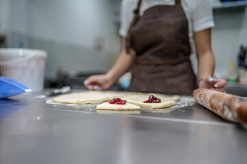 Obraz na płótnie Canvas Young woman making croissants in bakery kitchen