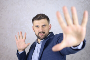 a man with a beard and a jacket gestures with his hands