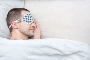 Siling man with mask for sleep sleeping in bed. Close up, top view