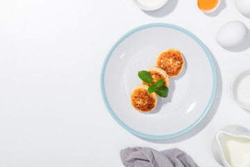 Cottage cheese, eggs, cream and yougurt on a white background - Flat lay with curd pancake - Recipe