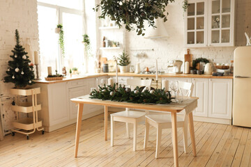 Interior of a light kitchen decorated with Christmas decorations and fir plants in natural materials and colors in a cozy home