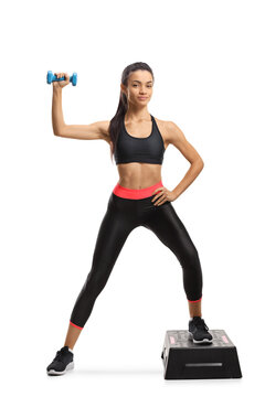 Full length portrait of a young female in sportswear exercising step aerobic with a dumbbell