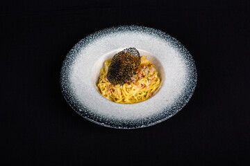 Pasta Carbonara with bacon on white plate and black background